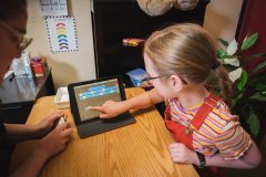 Young child engaged in learning on a computer tablet.
